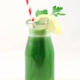 a green drink in a glass bottle with a straw and a lemon slice