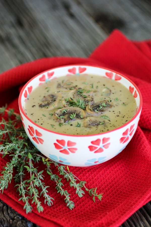 Creamy mushroom soup in a patterned bowl on a red cloth