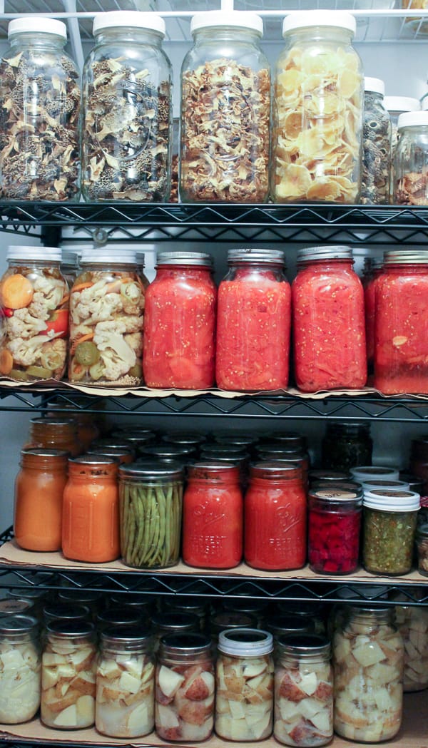 Rows of home-canned food in glass jars on pantry shelving