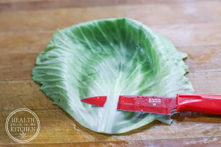Trimming the thick center vein from a softened cabbage leaf