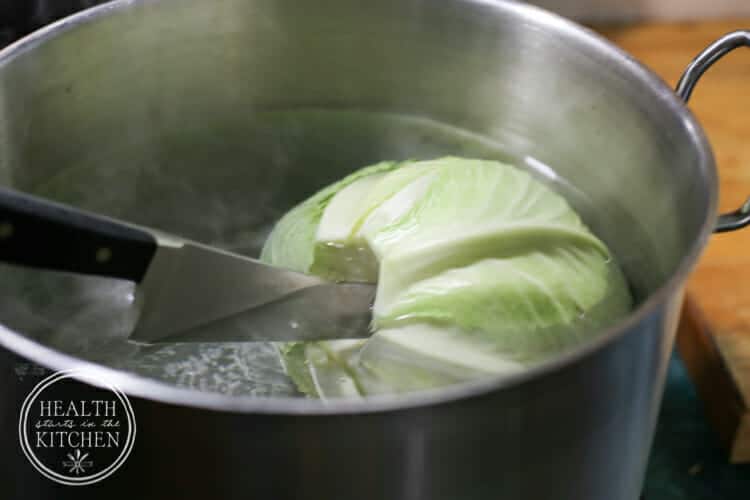 A head of green cabbage blanching in a pot of water