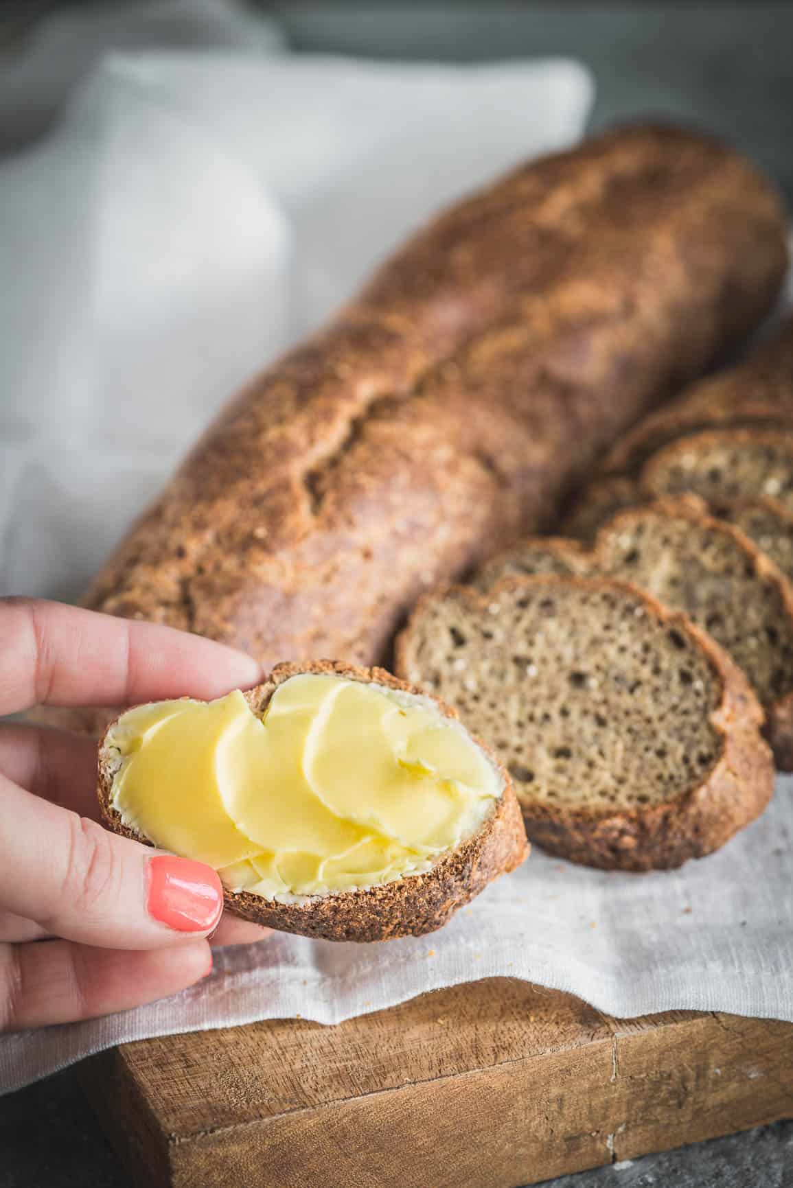 hand holding a slice of keto bread with butter