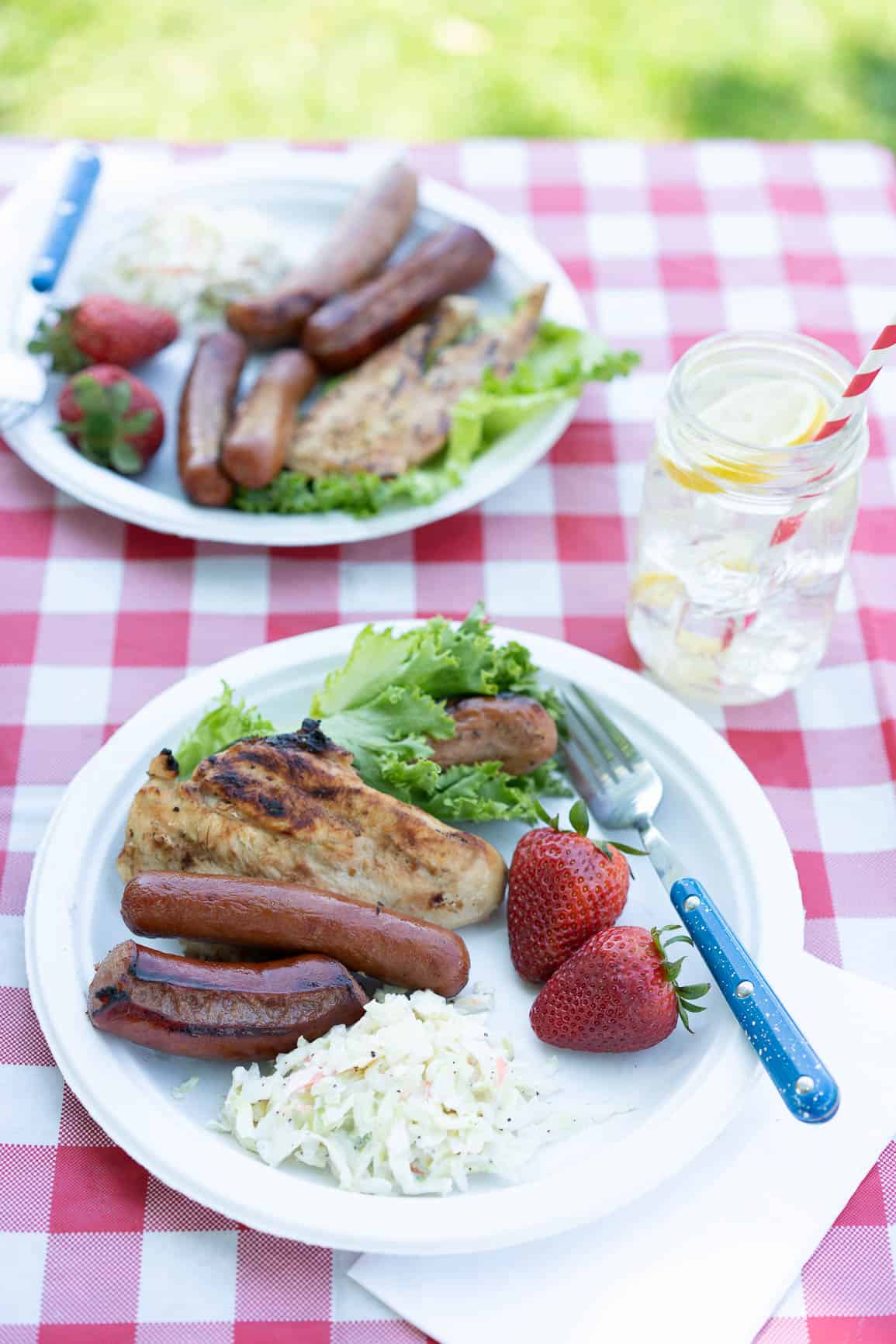 cookout plate of food; hot dogs, kielbasa, chicken, strawberries, and Cole slaw.