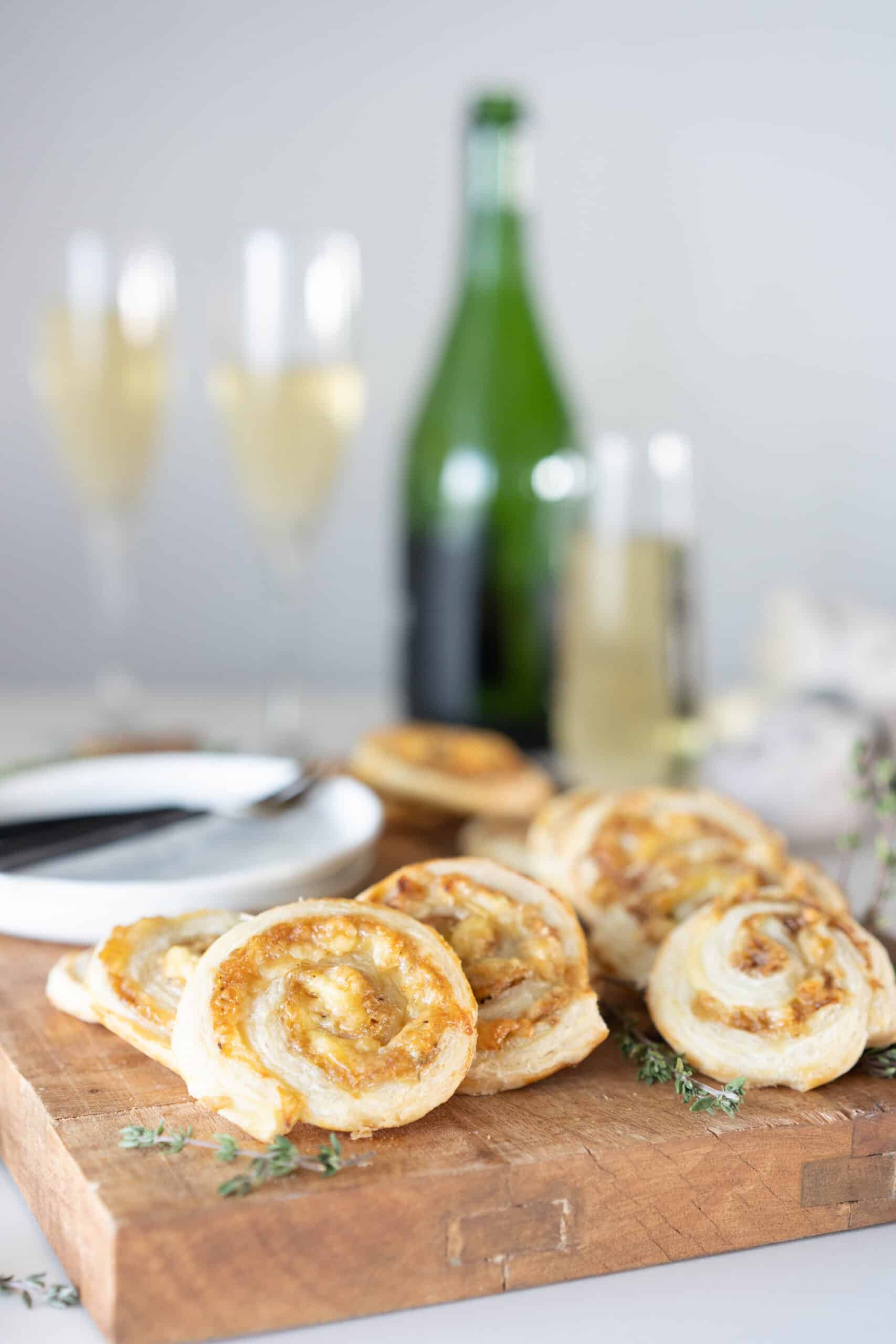 French onion soup spirals on a wooden cutting board with a bottle of wine in the background 