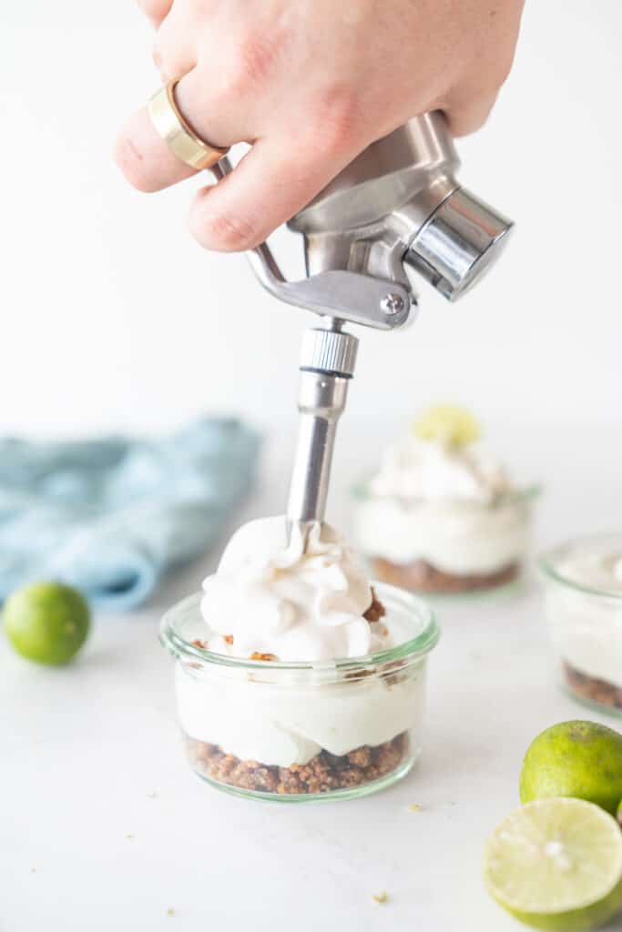 topping a key lim pie in a jar with whipped cream
