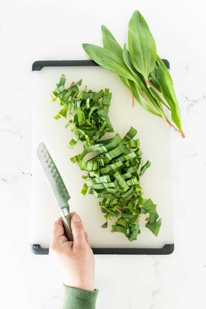 Ramp leaves being cut on a white cutting board