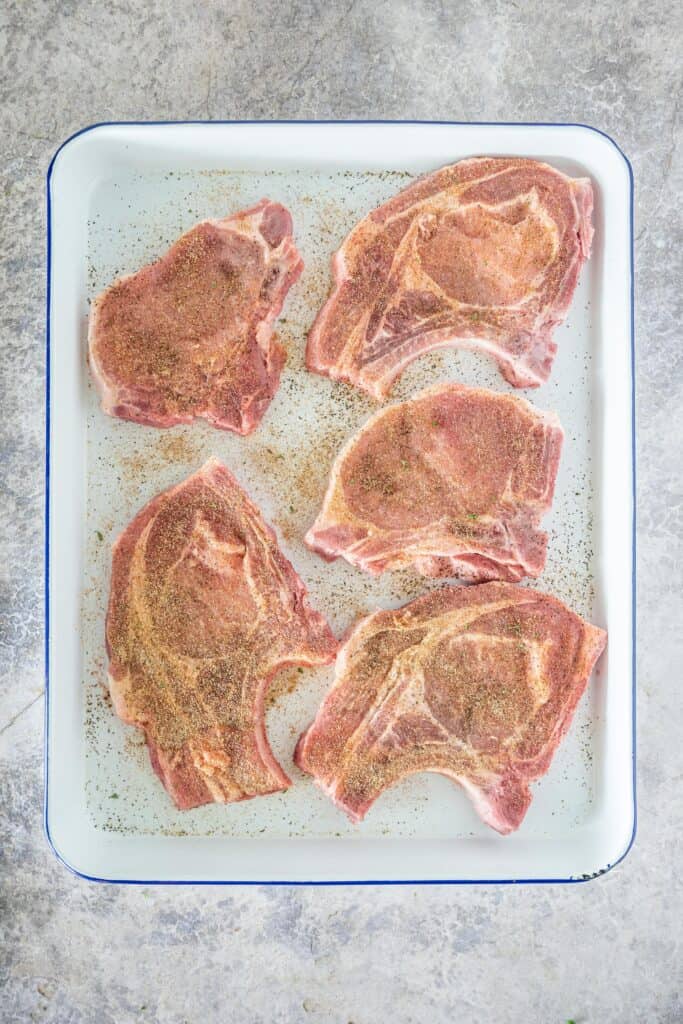 seasoned pork chops on a white butcher tray