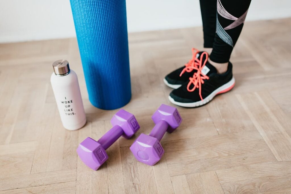 a pair of purple dumbbells next to a yoga mat