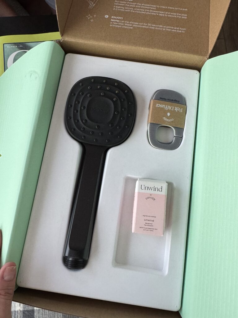 a hand holding a box with a shower head and a small box of erasers