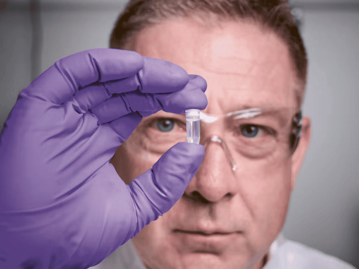 a man wearing glasses and holding a small tube