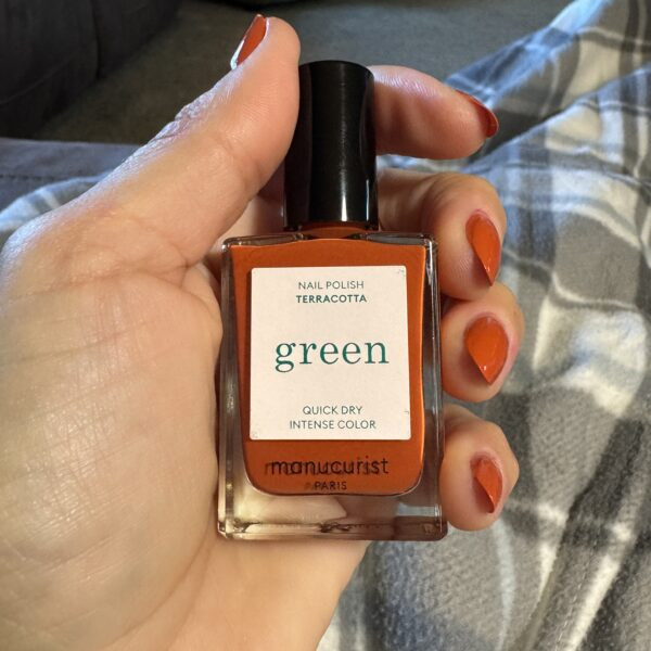 Hand holding orange nail polish bottle