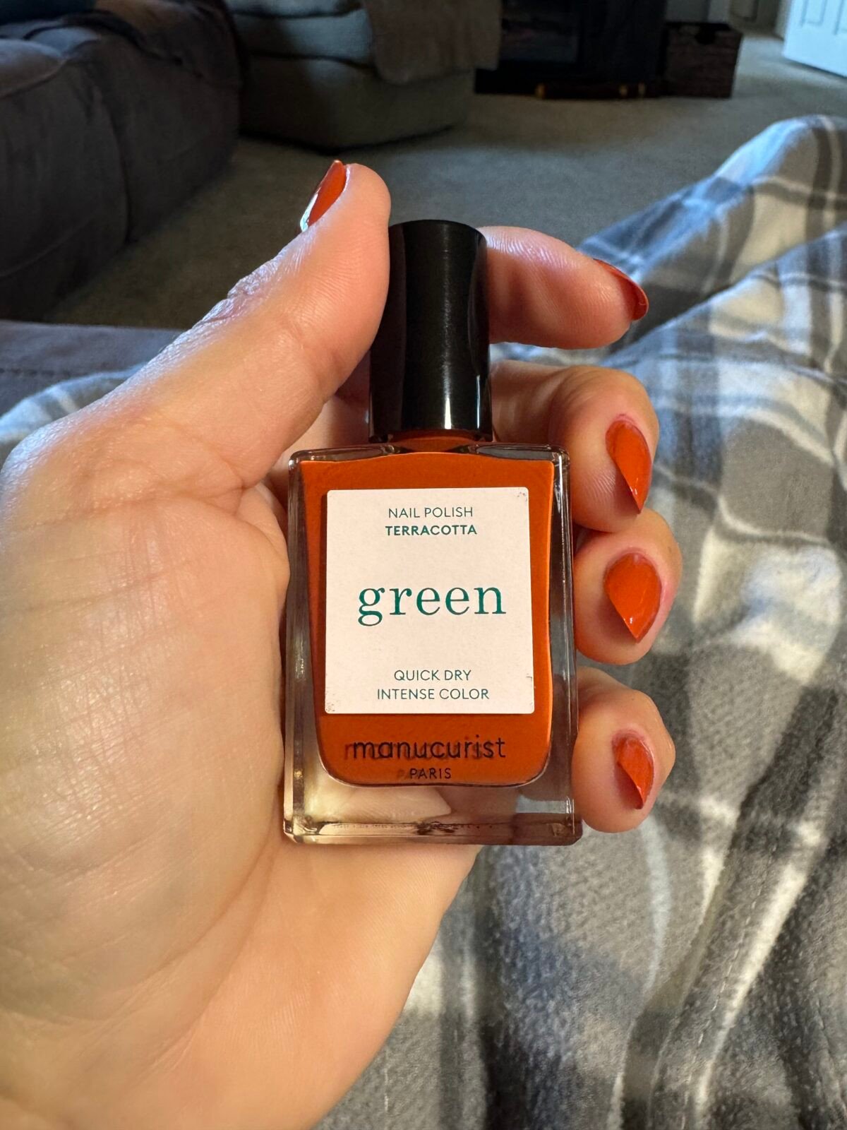 Hand holding orange nail polish bottle