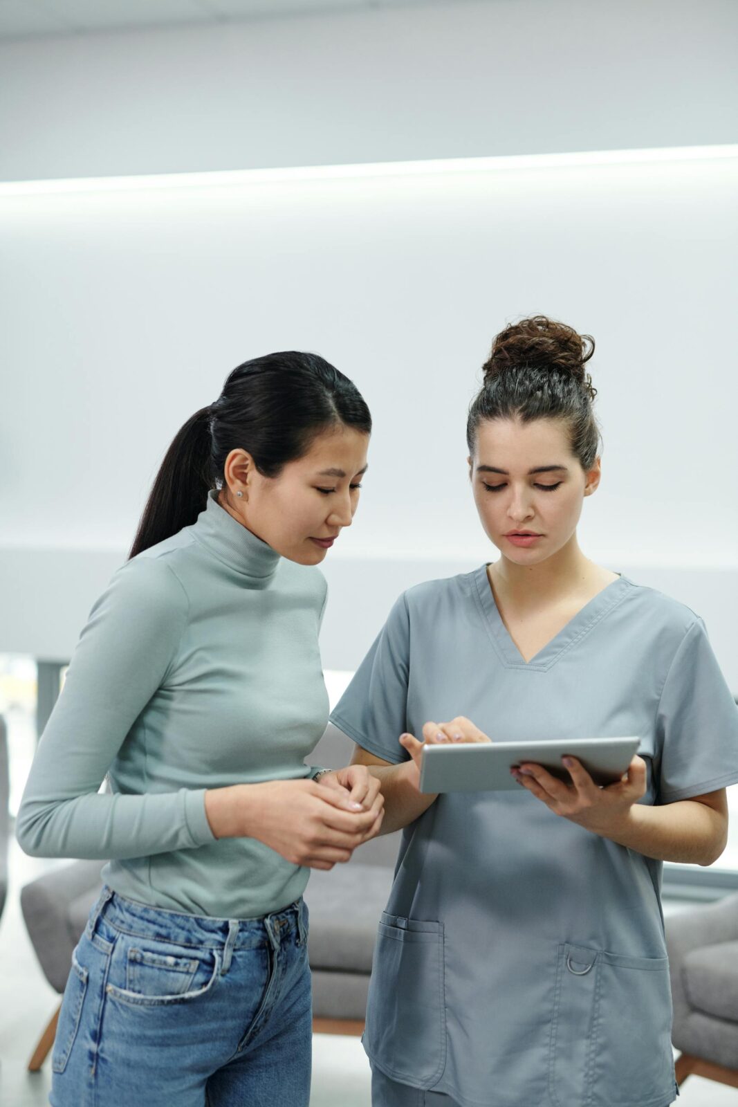 Healthcare professional using a tablet during a consultation inside a clinic.