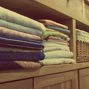Tidy wooden cabinet with neatly stacked towels and decorative baskets in an indoor setting.