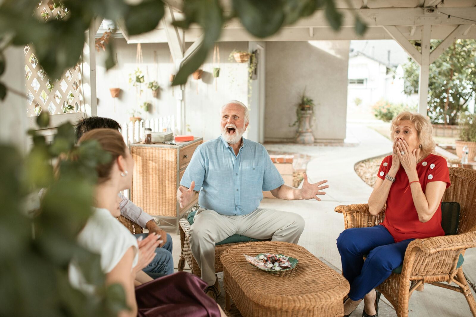 Surprised grandparents having a lively conversation in an outdoor patio setting with family.