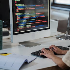 Close-up of a person typing code on a computer in an office setting.