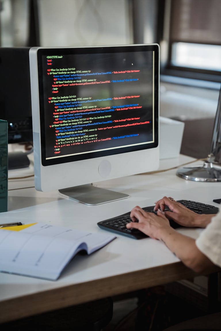 Close-up of a person typing code on a computer in an office setting.