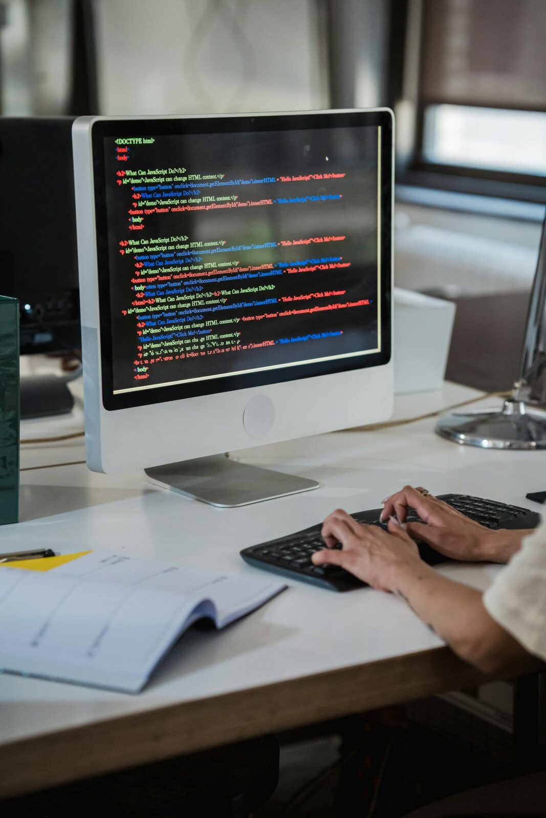 Close-up of a person typing code on a computer in an office setting.