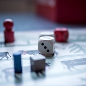 Close-up view of board game pieces and dice on a game board. Perfect for recreation and strategy themes.