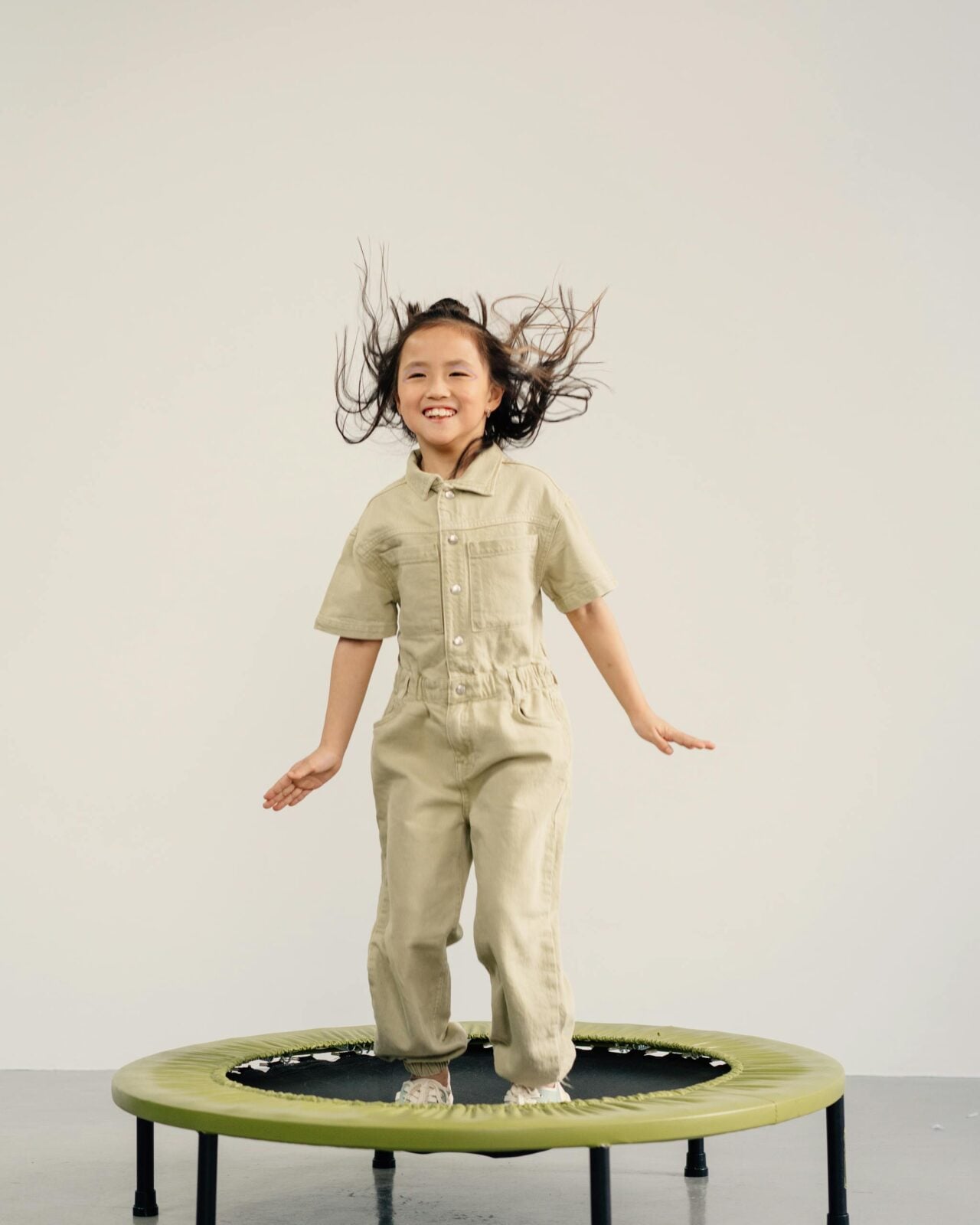 Joyful young girl jumping on a trampoline with a playful smile, showcasing fun and energy.