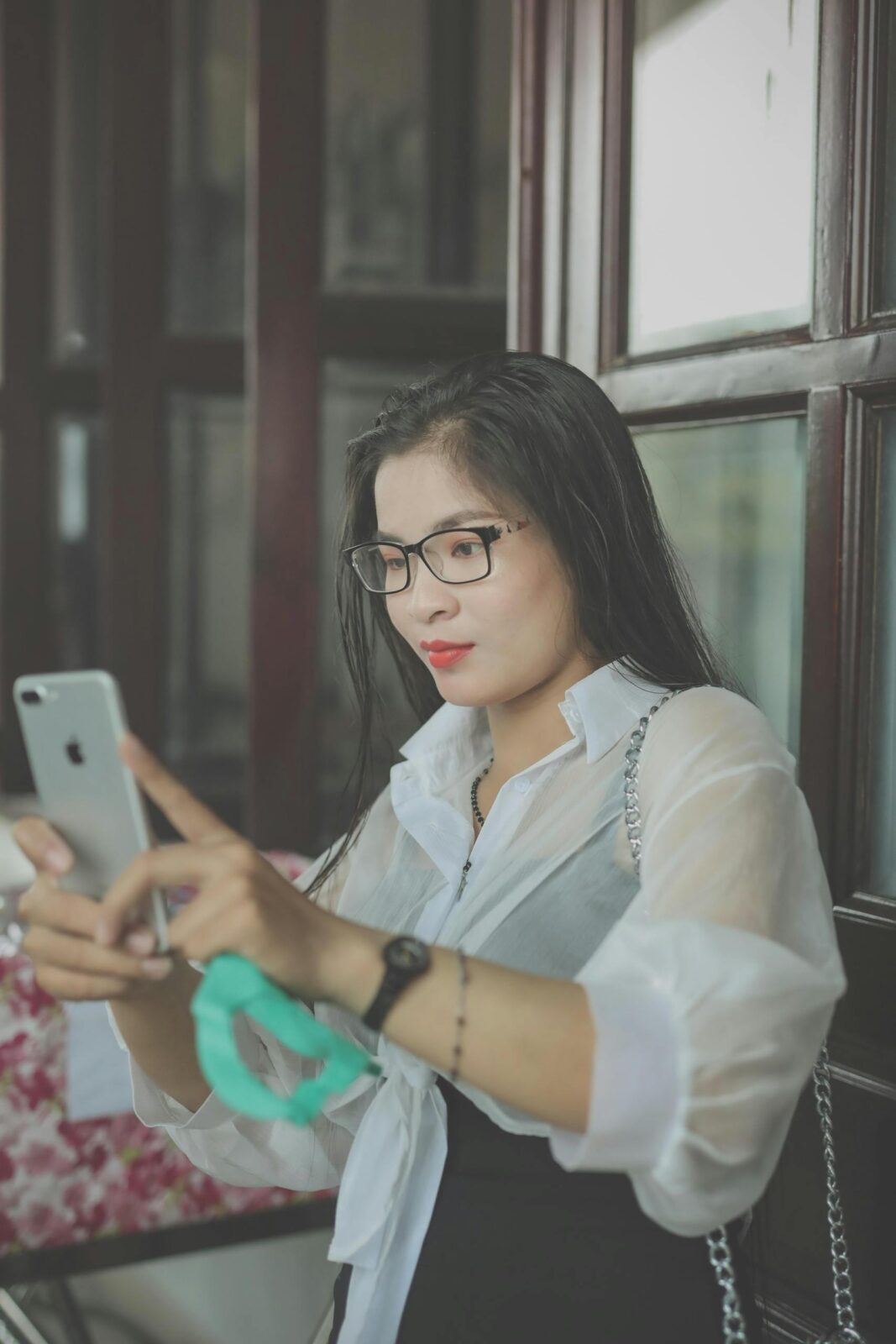 Young Asian woman touching smartphone screen indoors for communication and entertainment.