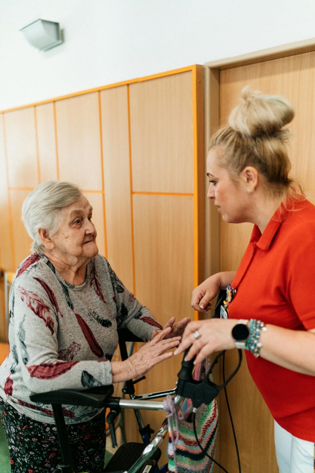 A caregiver assists an elderly woman in a retirement home corridor, fostering companionship and support.