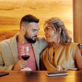 A loving couple sharing a romantic moment with red wine in a stylish restaurant.