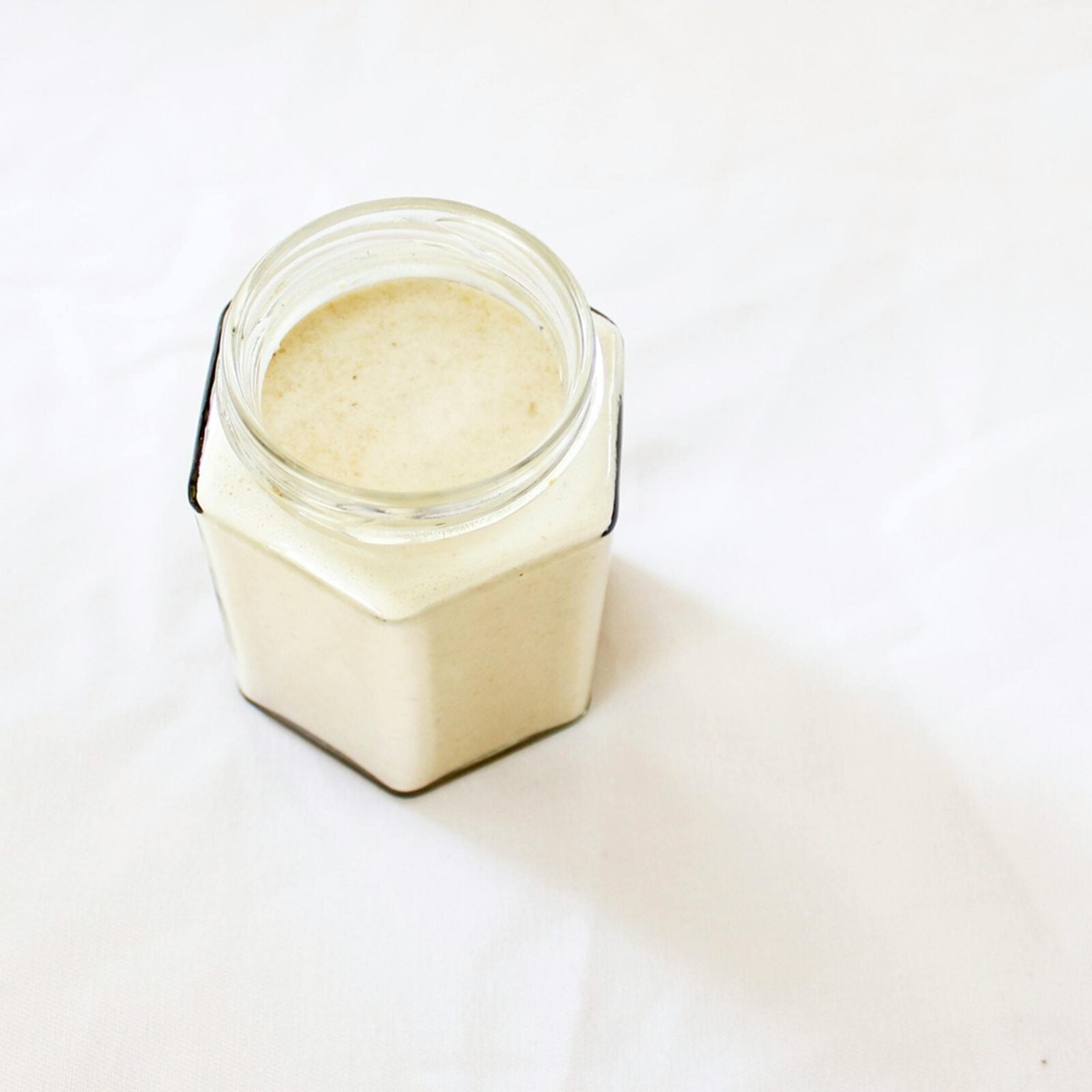 Close-up of a glass jar filled with milk on a white background.