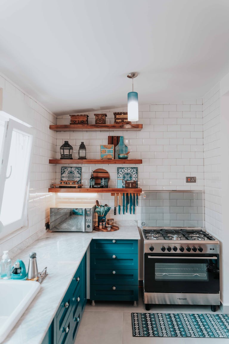 Bright modern kitchen with shelves, stove, and teal cabinets.