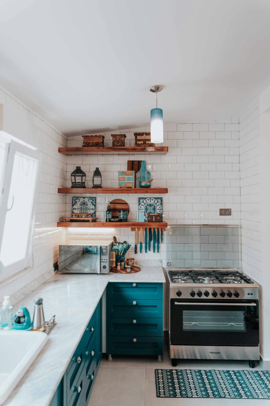 Bright modern kitchen with shelves, stove, and teal cabinets.