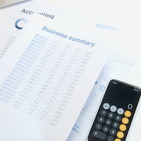 Business summary sheet with a calculator on a desk for financial analysis.