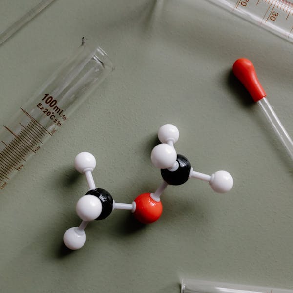 Close-up of a molecular model surrounded by laboratory equipment like pipettes and test tubes.