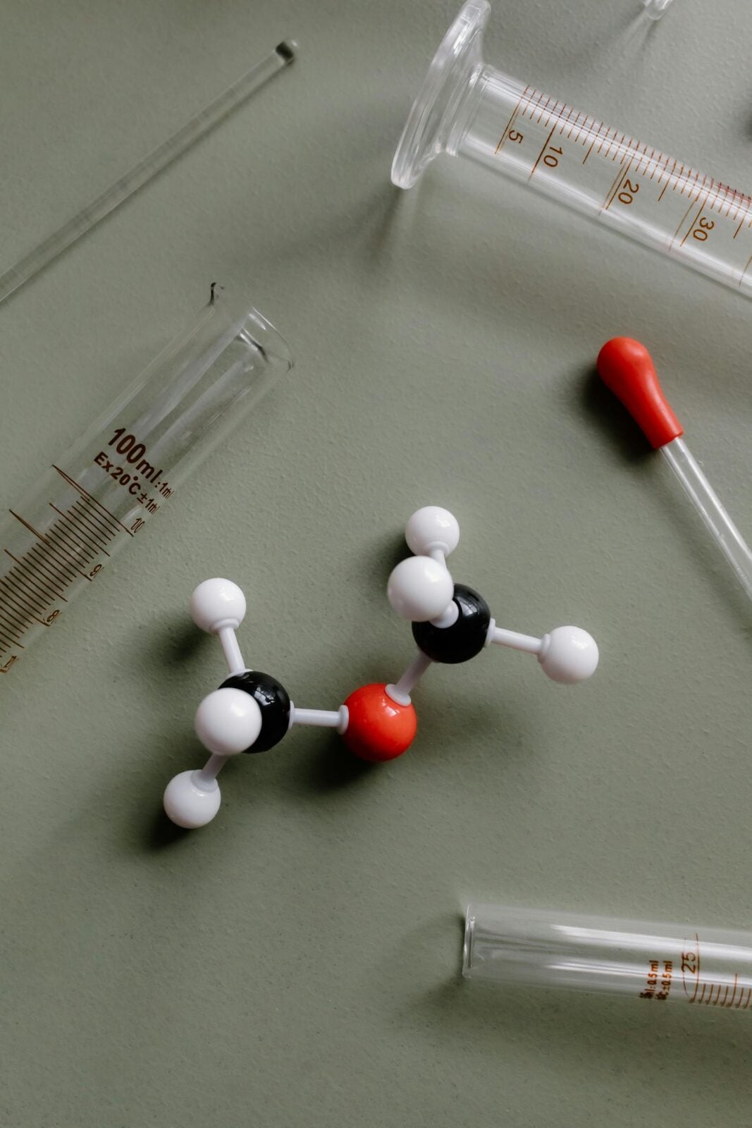 Close-up of a molecular model surrounded by laboratory equipment like pipettes and test tubes.