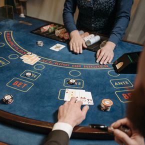People playing a lively card game at a casino table with chips and a dealer.