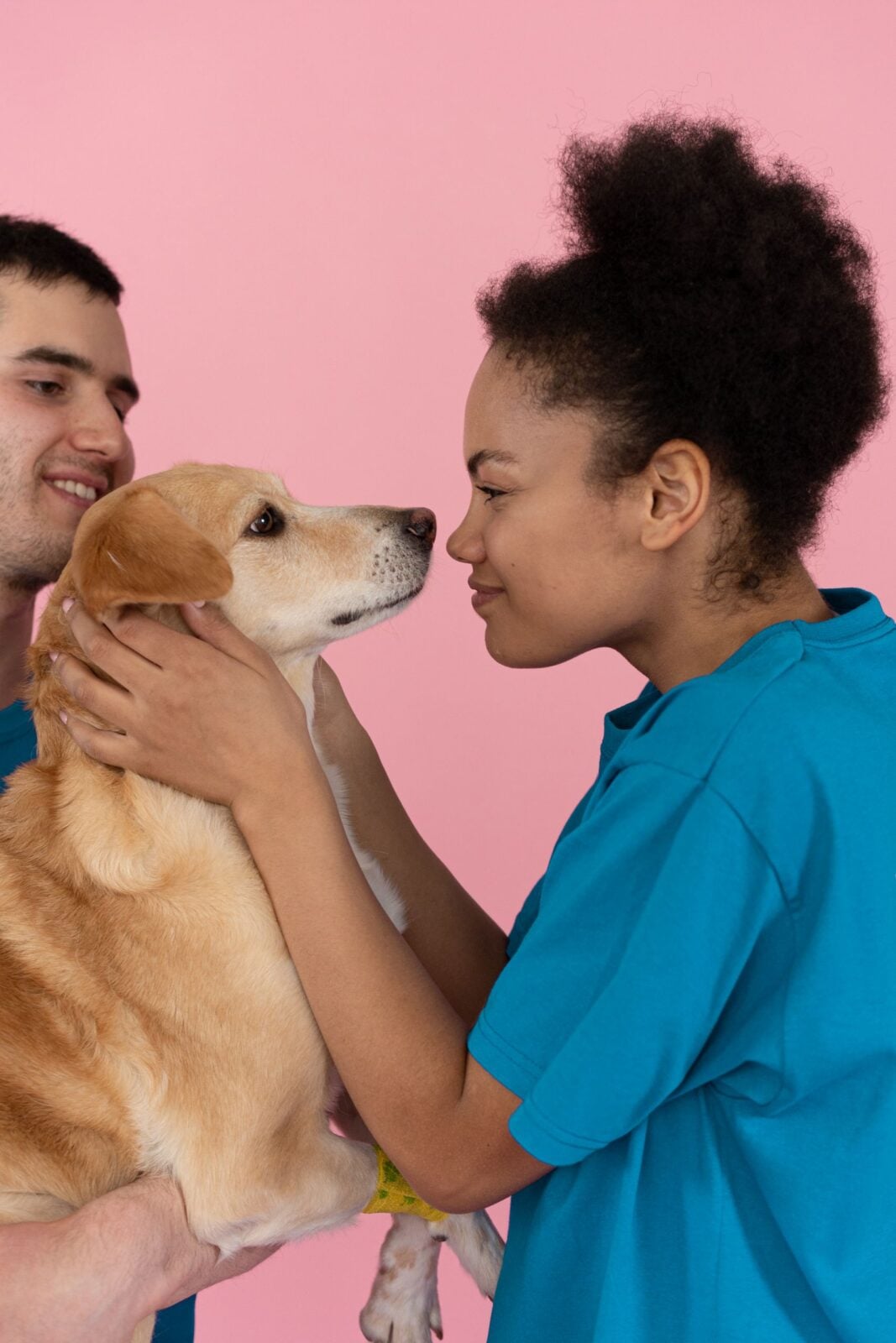 Cheerful moment of two volunteers bonding with a dog in a studio.