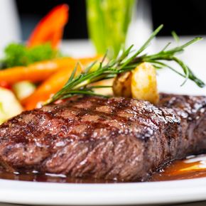 Close-up of a juicy grilled steak with colorful vegetables on a plate, perfect for a gourmet meal.