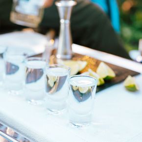 Close-up of tequila shots with lime on a bar counter being prepared by a bartender.
