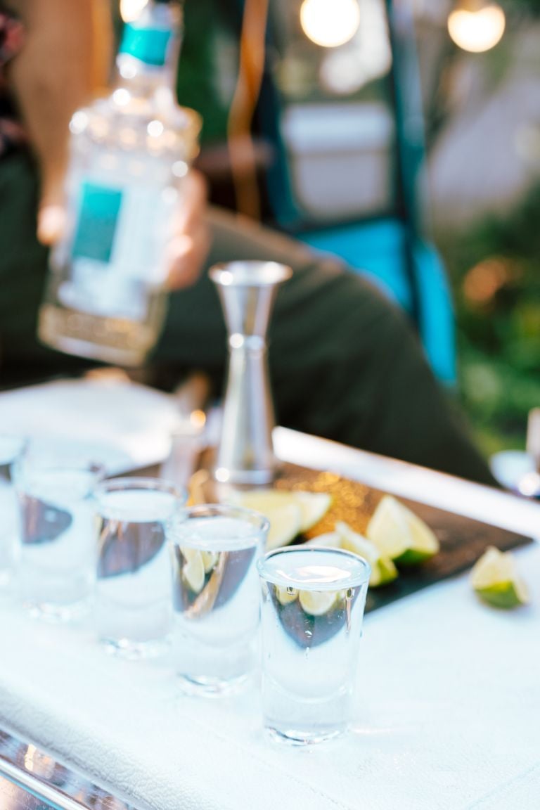 Close-up of tequila shots with lime on a bar counter being prepared by a bartender.