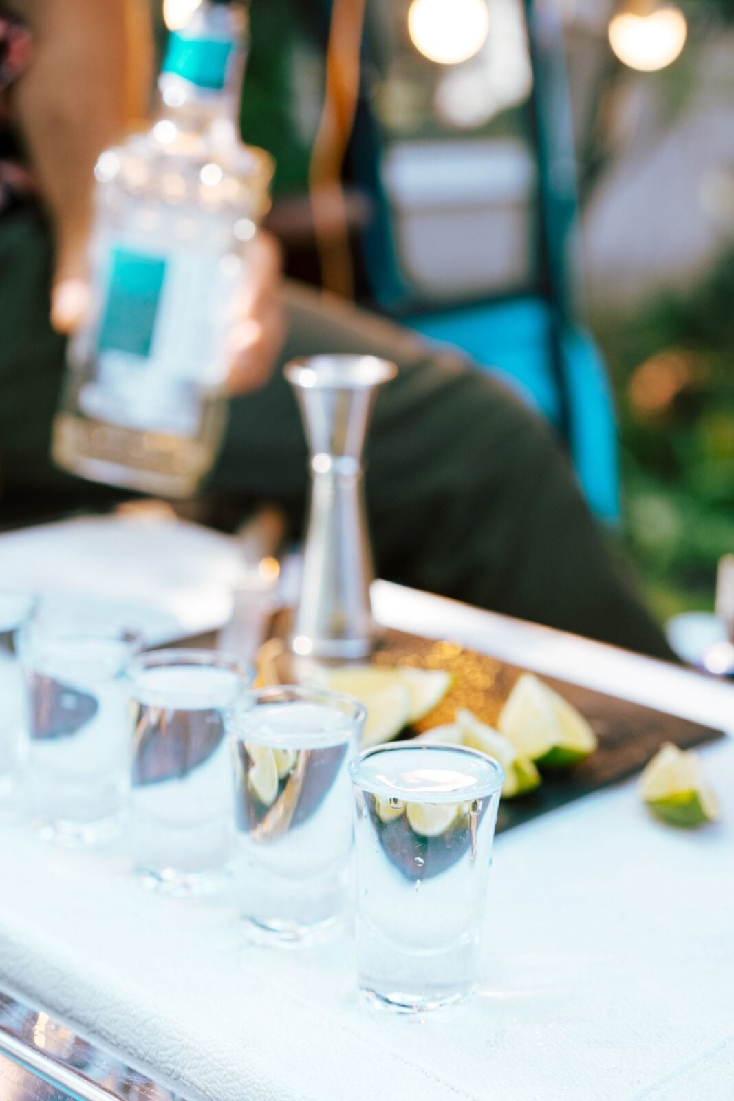 Close-up of tequila shots with lime on a bar counter being prepared by a bartender.