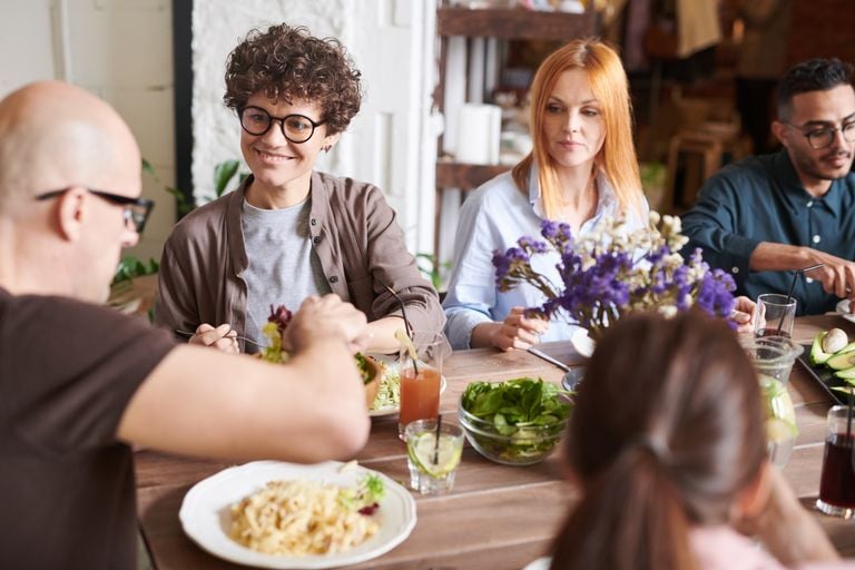 A diverse group of friends dining together at a cozy indoor setting, sharing and enjoying a meal.