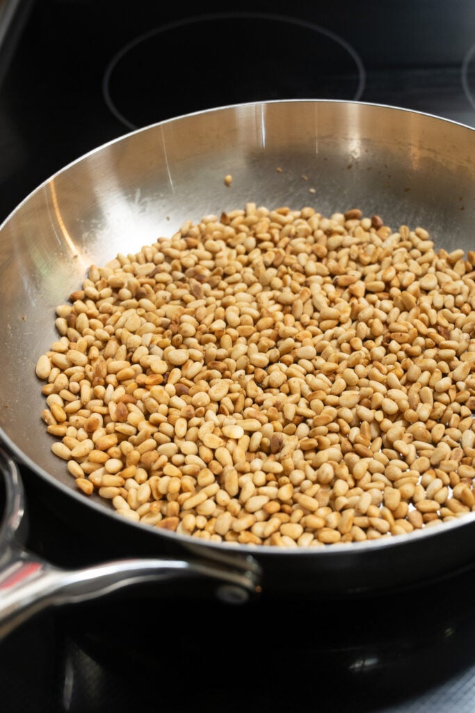 Pine nuts toasting in a stainless steel skillet