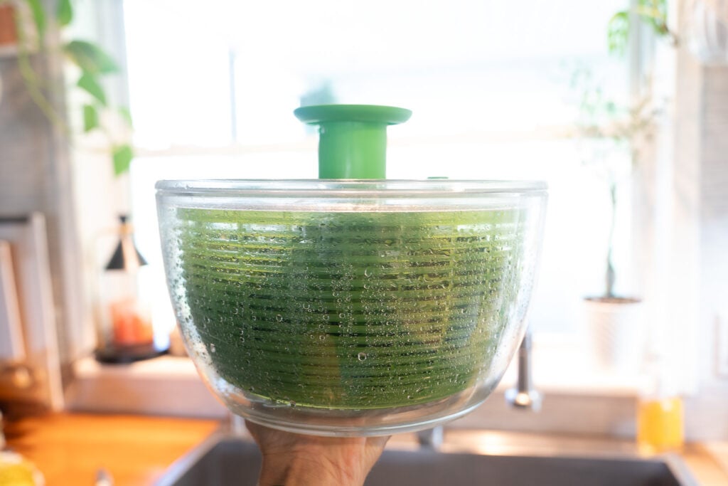 Salad spinner filled with fresh basil leaves