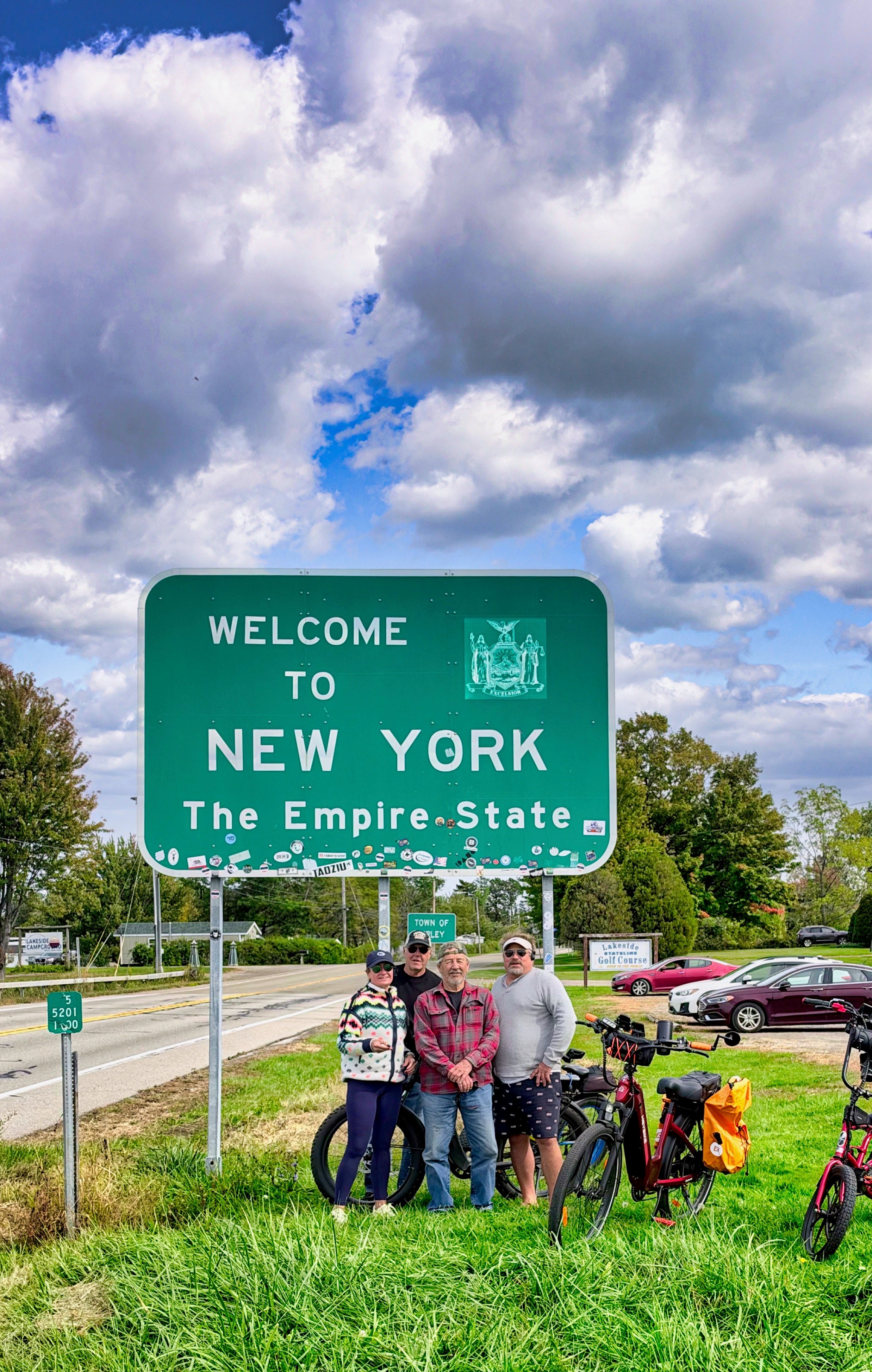 Hayley and friends with their e-bikes beside the Welcome to New York sign