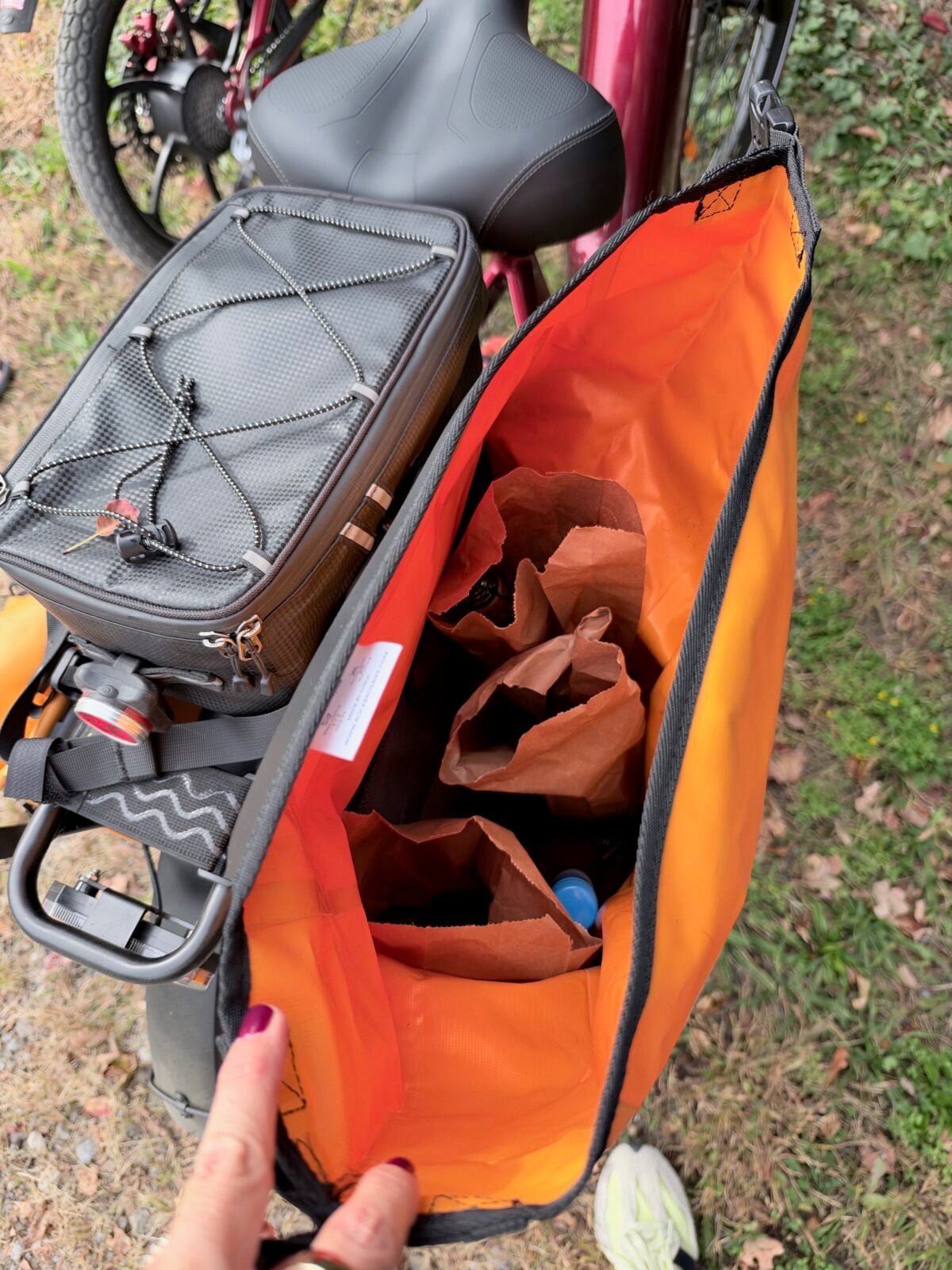 Open orange pannier on Ruby holding wine bottles in brown paper bags.