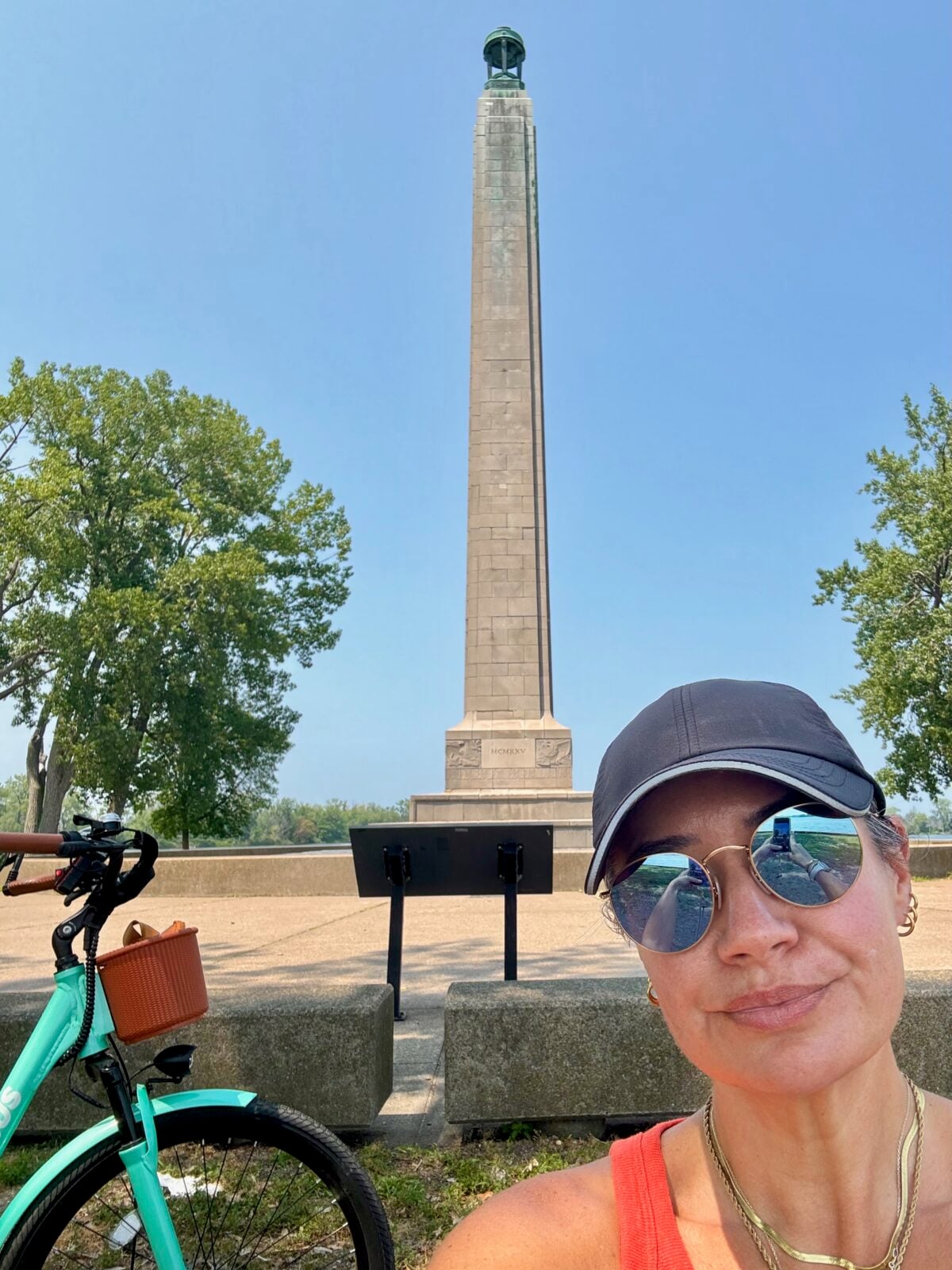 Hayley taking a selfie beside her turquoise e-bike at a monument
