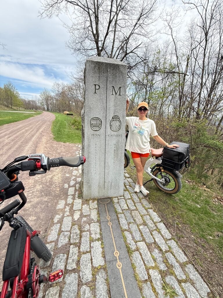 Hayley with her e-bike beside the Pennsylvania and Maryland boundary marker.