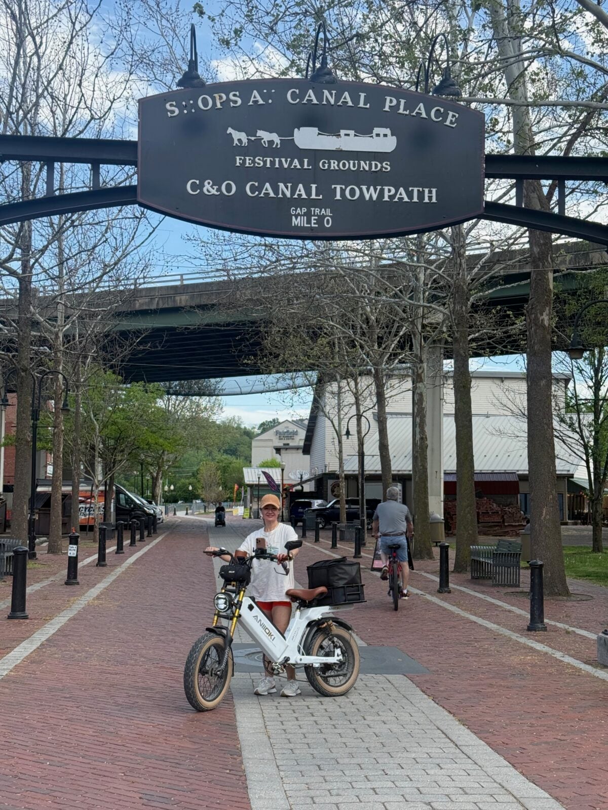 Hayley standing with Comet beneath the Canal Place and GAP Trail Mile 0 sign.