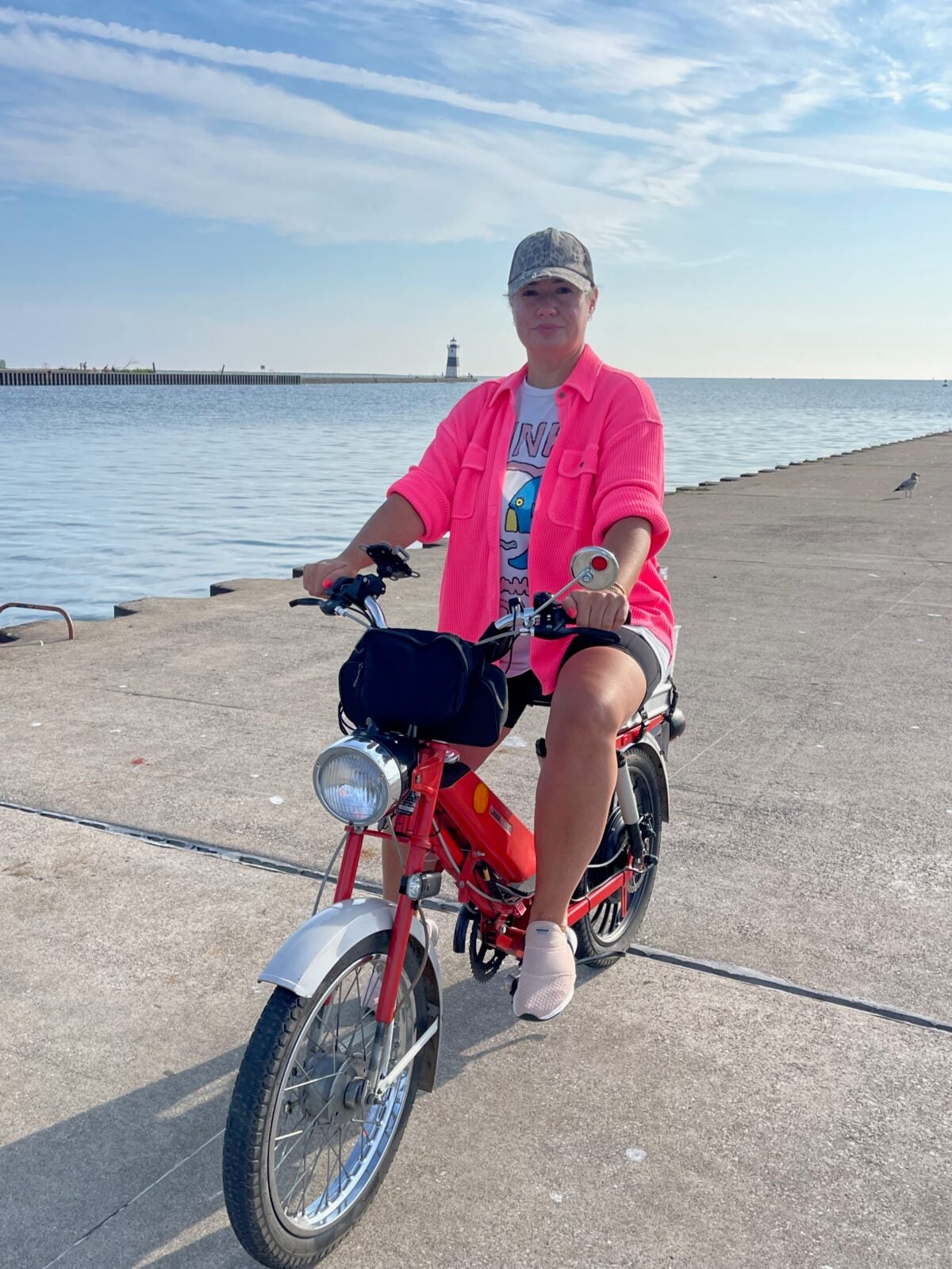 Hayley in a pink jacket with her e-bike beside the lake