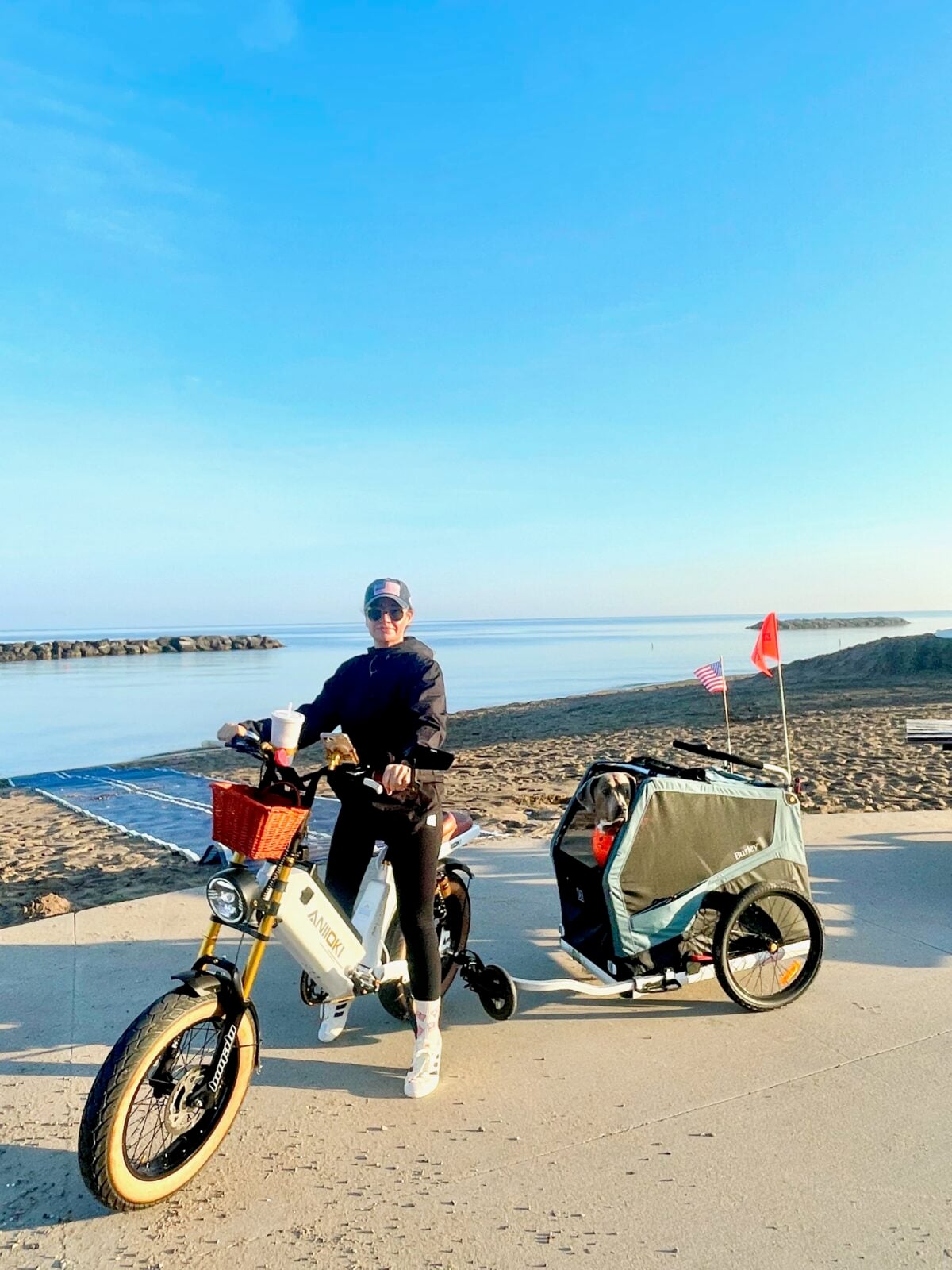 Hayley with Comet and Argos in his dog bike trailer beside the lake
