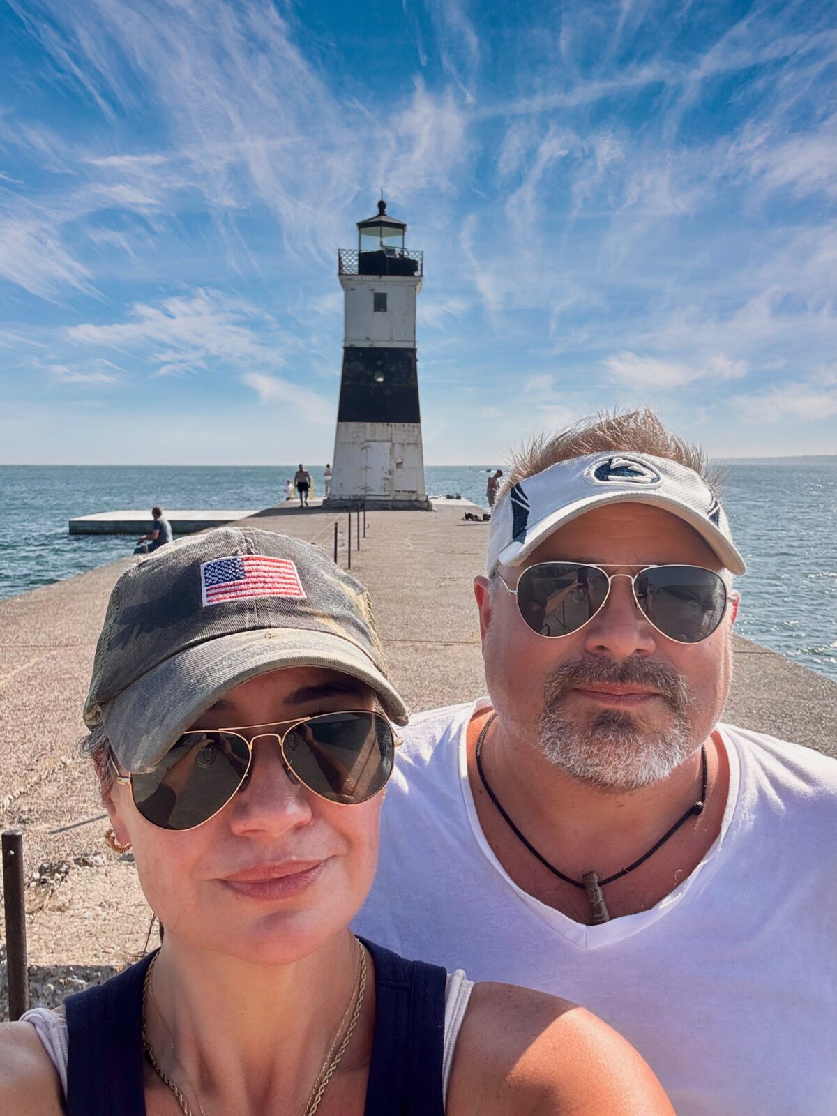 Hayley and Ray taking a selfie beside the water with a lighthouse behind them
